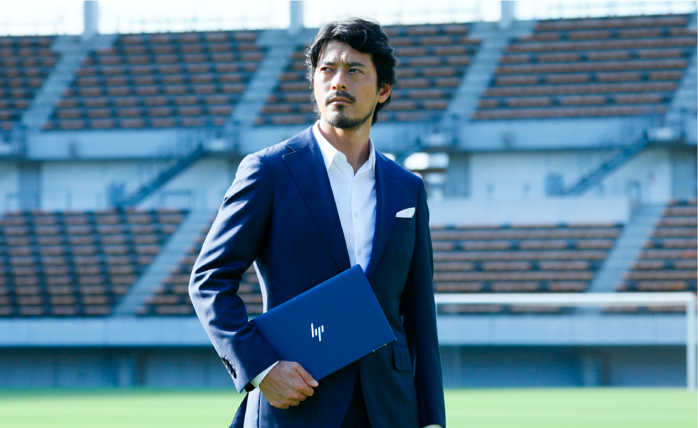 サッカースタジアムで HP Elite Dragonfly を持つ鈴木啓太氏